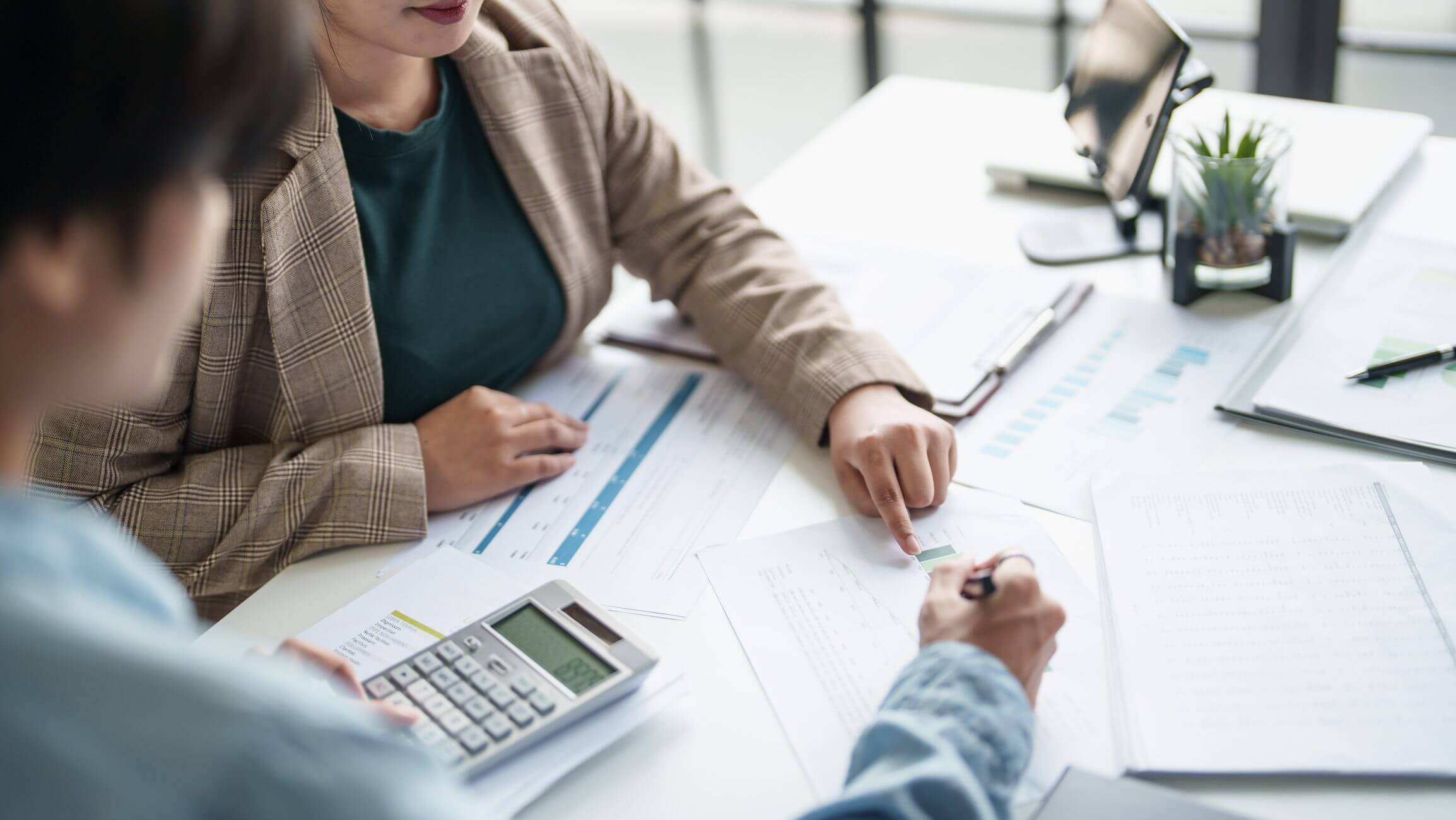 Two professionals reviewing financial charts and data together at a desk.