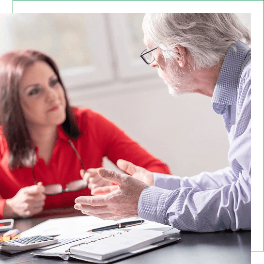 A woman in red listens attentively to an older man during a discussion.