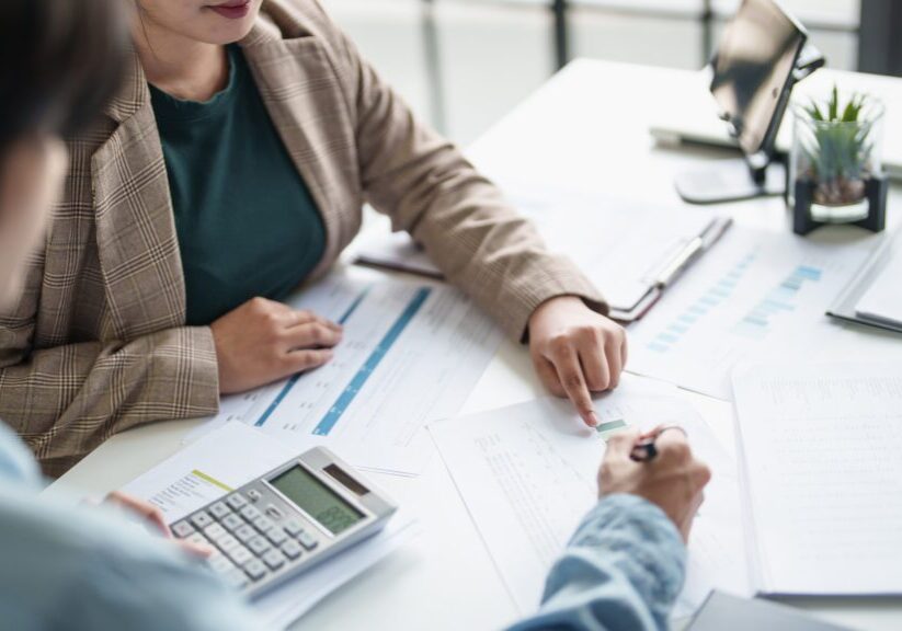 Two professionals reviewing financial charts and data together at a desk.